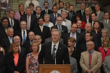 Governor Baker stands with crowd of officials at municipal modernization bill signing