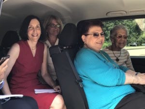 Four women pose for picture in a car.
