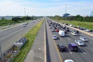 A highway with traffic backed up going in one direction, with barely any traffic headed in the opposite direction