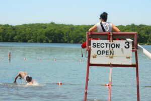 lifeguard sits on town watching man swim in lake