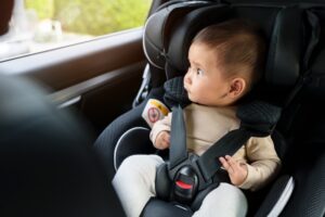 happy infant baby sitting in car seat and looking out of the window, safety chair travelling